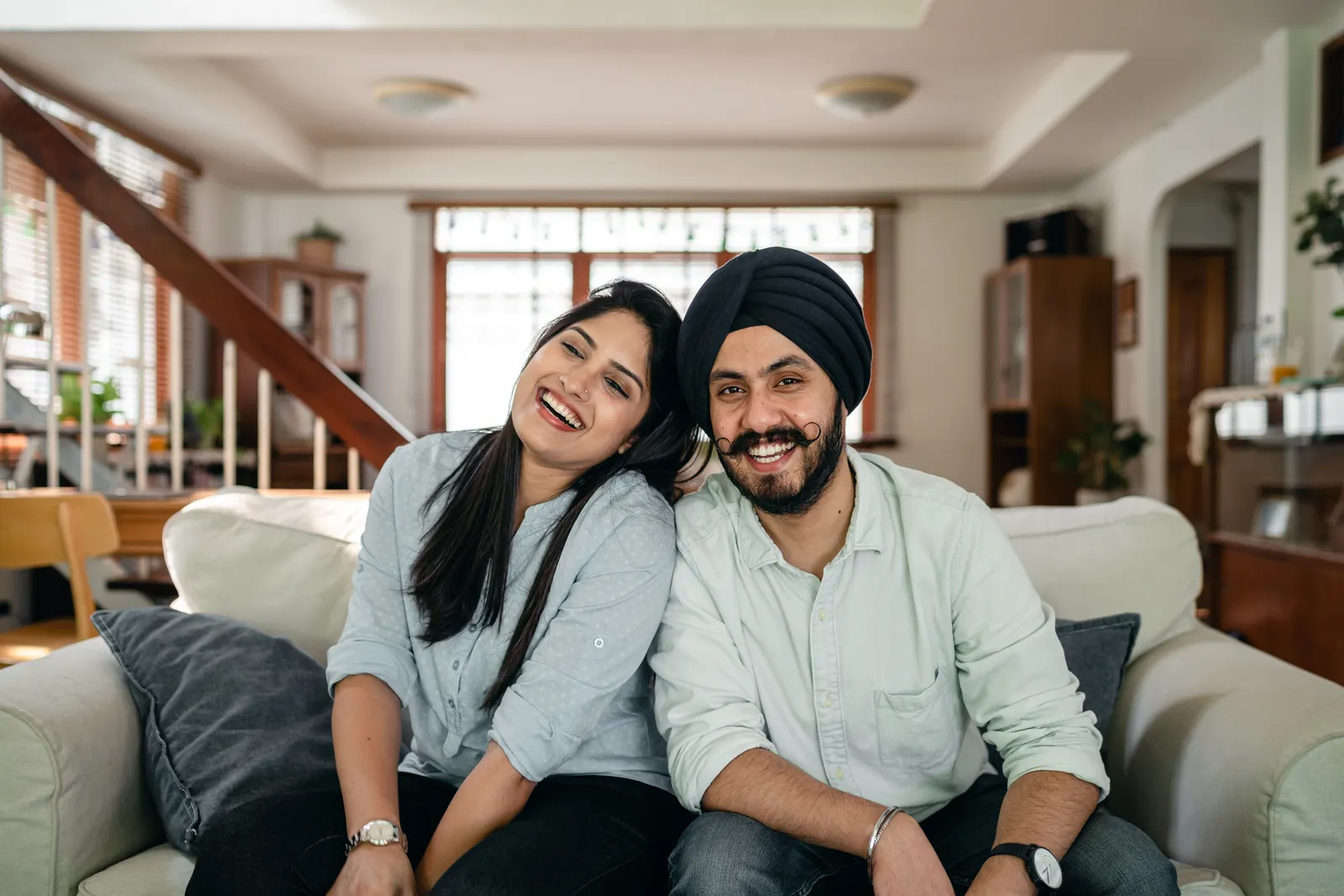 A fictional couple smiling together on a couch