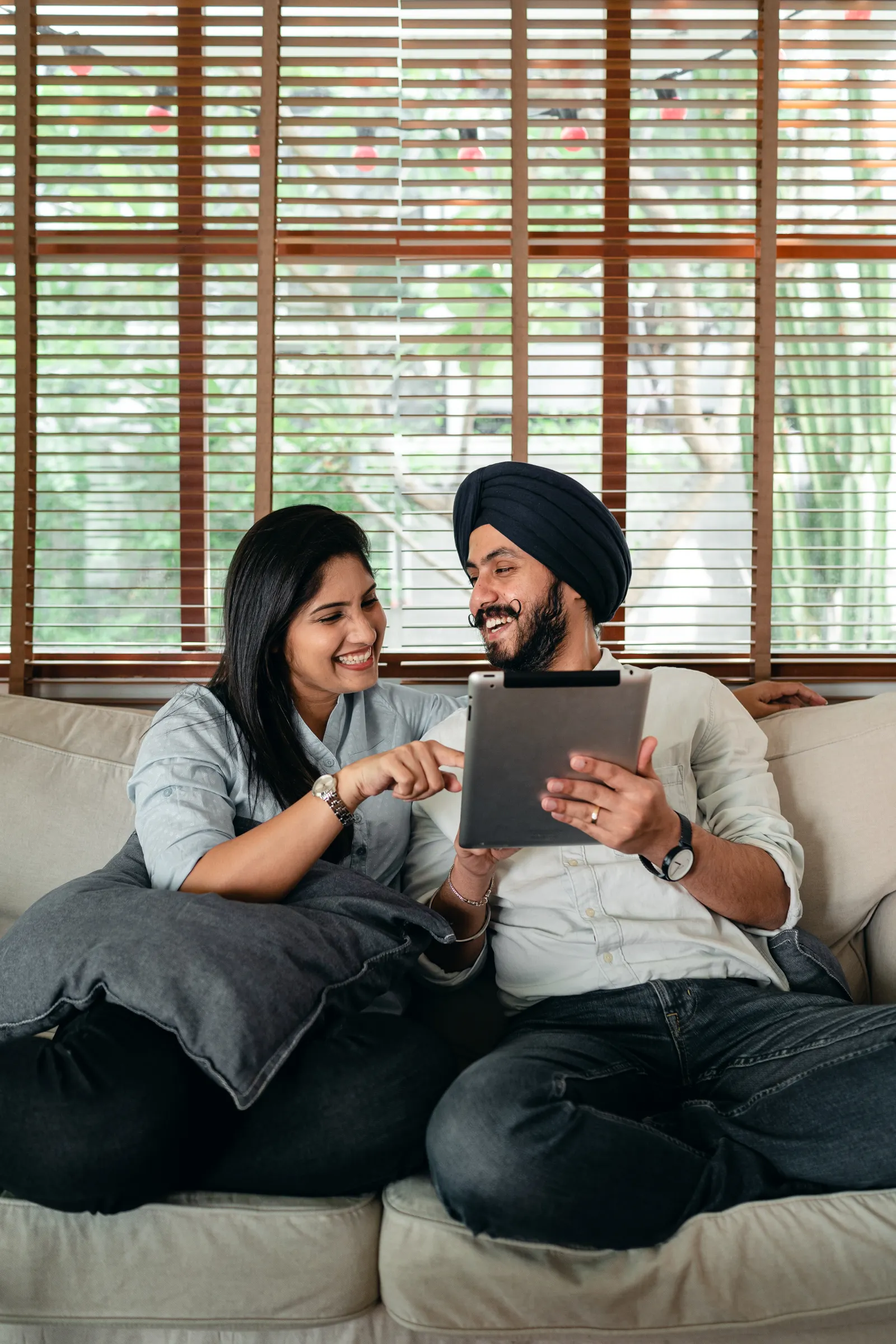 A fictional couple sharing a tablet and laughing at home